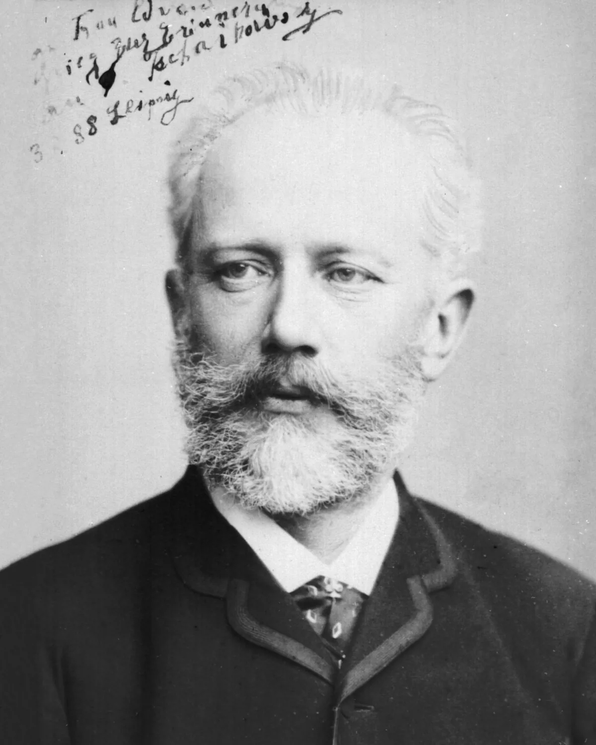 A black-and-white studio photograph of Pyotr Ilyich Tchaikovsky in 1888, a grey-bearded man in a dark jacket and tie looking to the side